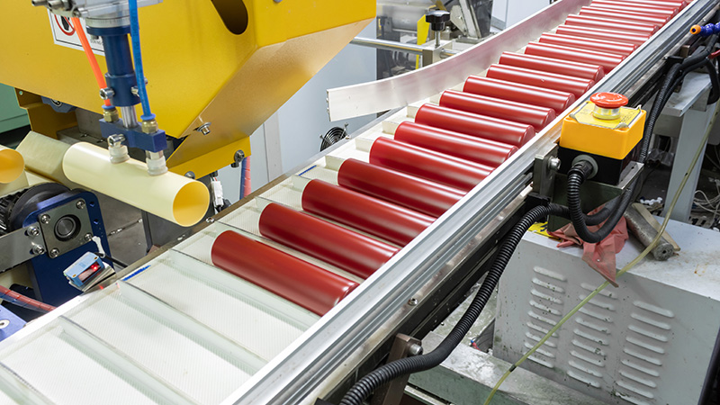 Factory conveyor belt: Red plastic cosmetic bottles in production process Conveyor belt in factory with red plastic cosmetic bottles, part of production line