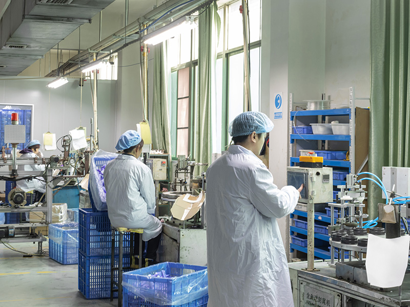 Factory workers producing cosmetic jars with automated machinery, focusing on PET/PP jars Workers in cleanroom suits operate machines for PET/PP cosmetic jars production in factory