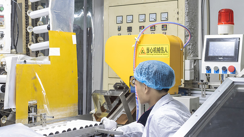 Worker in cleanroom suit monitors PET bottle production line for packaging bottles