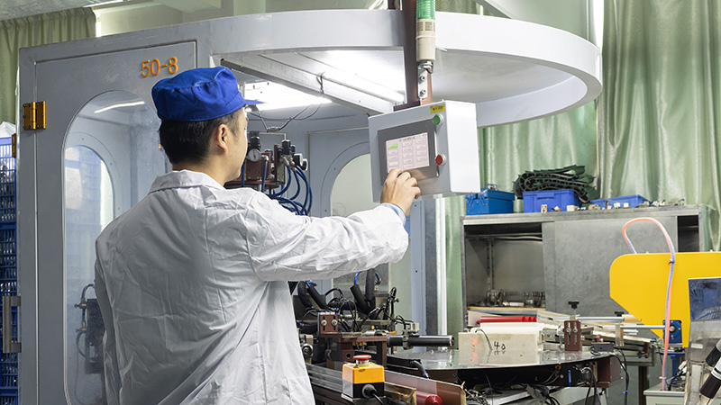 Worker operating machine in cosmetic bottle factory, handling PET bottle production